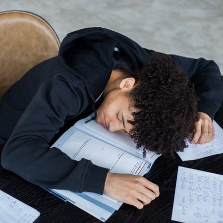 A man who's so bored that he's fallen asleep in his books. 